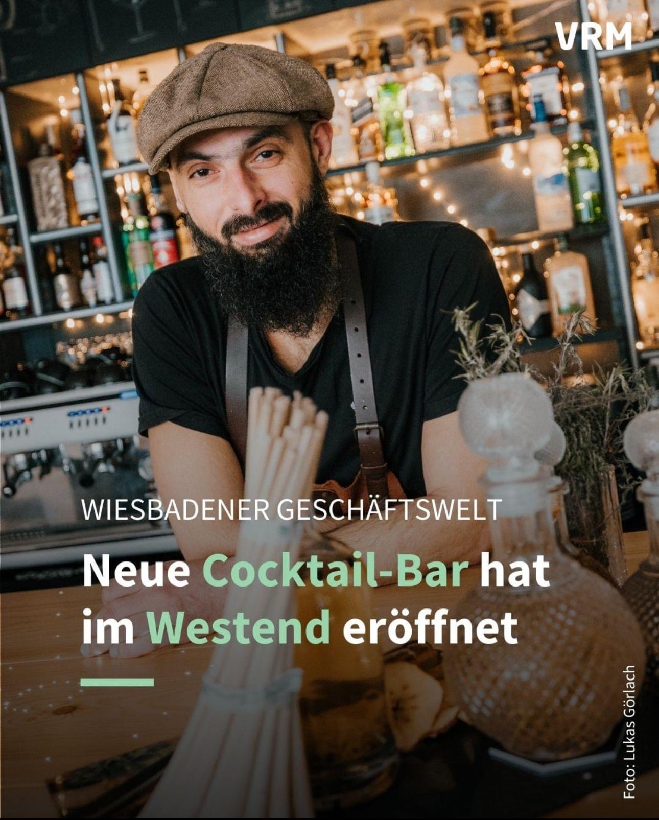 Bartender smiling in a new cocktail bar with shelves of bottles and decorative lights in the background.